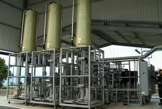 Industrial skid-mounted processing unit with three tall vertical vessels and a metal frame under a canopy.